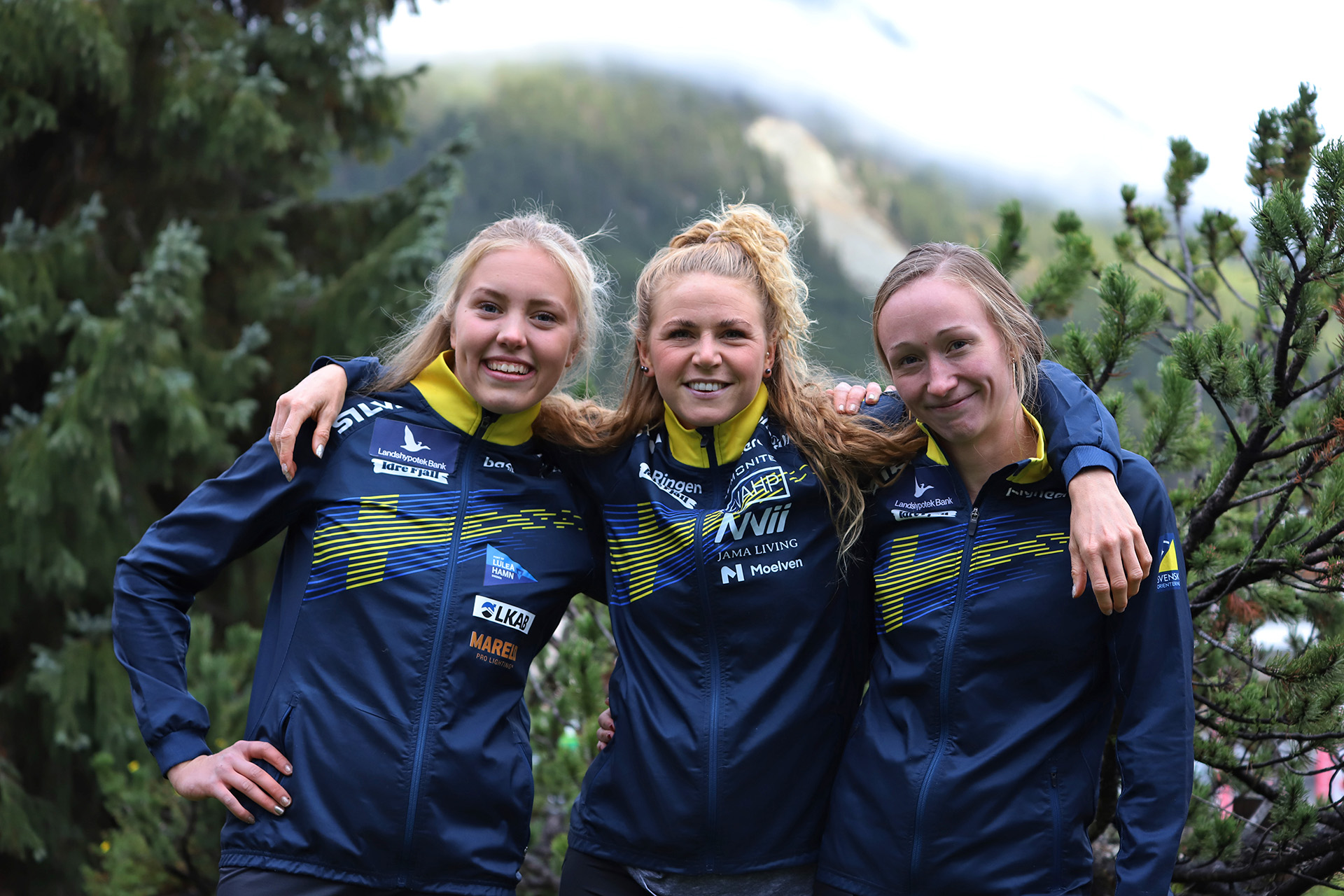 Hanna Lundberg, Karolin Ohlsson och Johanna Ridefelt med glada leenden och schweiziskt berg i bakgrunden.