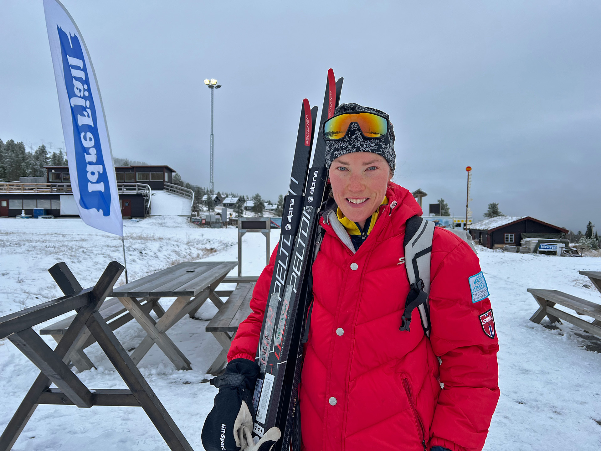 Tove Alexandersson med ett leende och två par skidor mot axeln på Idrefjäll.